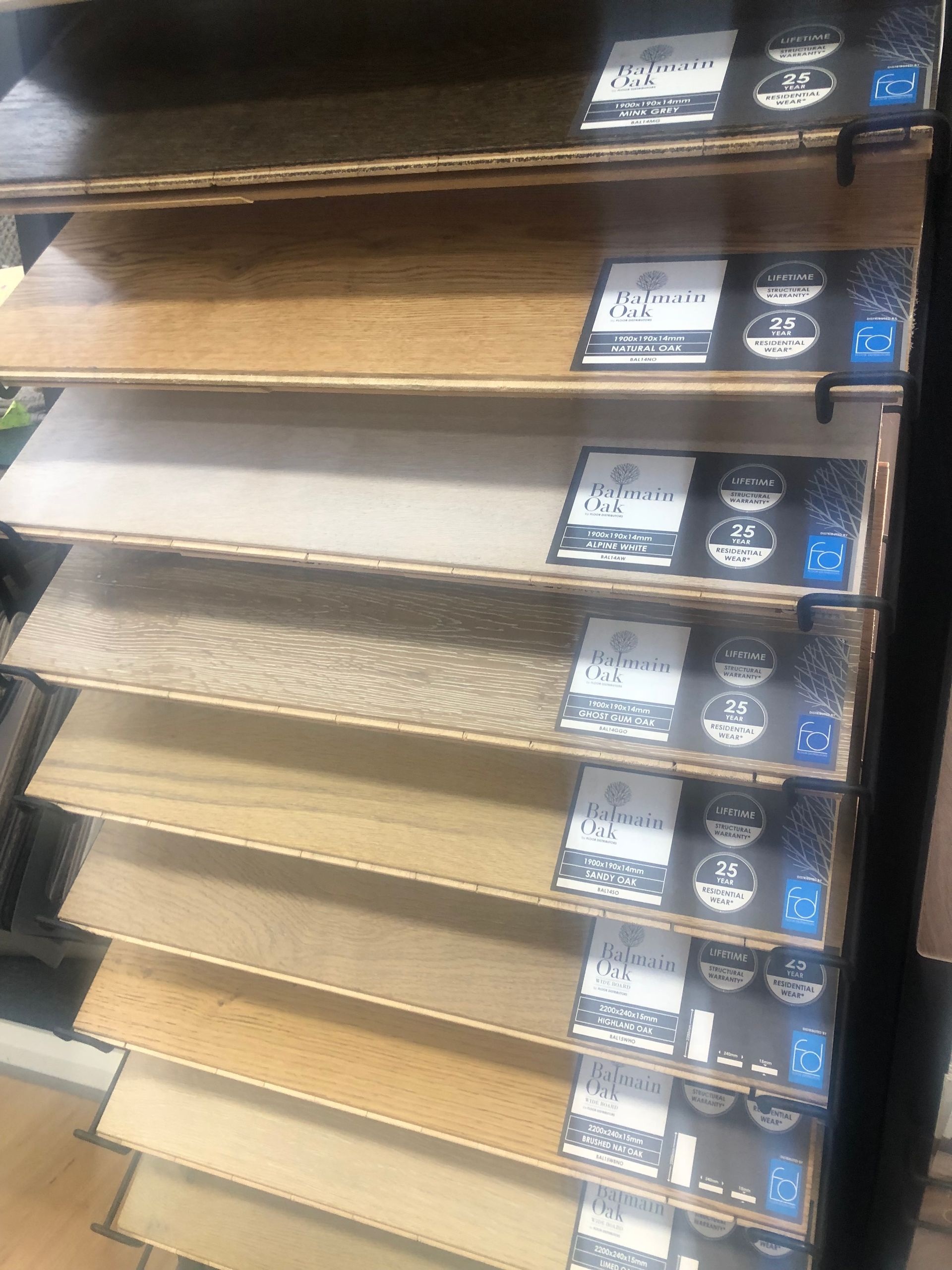 Display of various wooden flooring samples on a rack, showcasing different colors and textures.