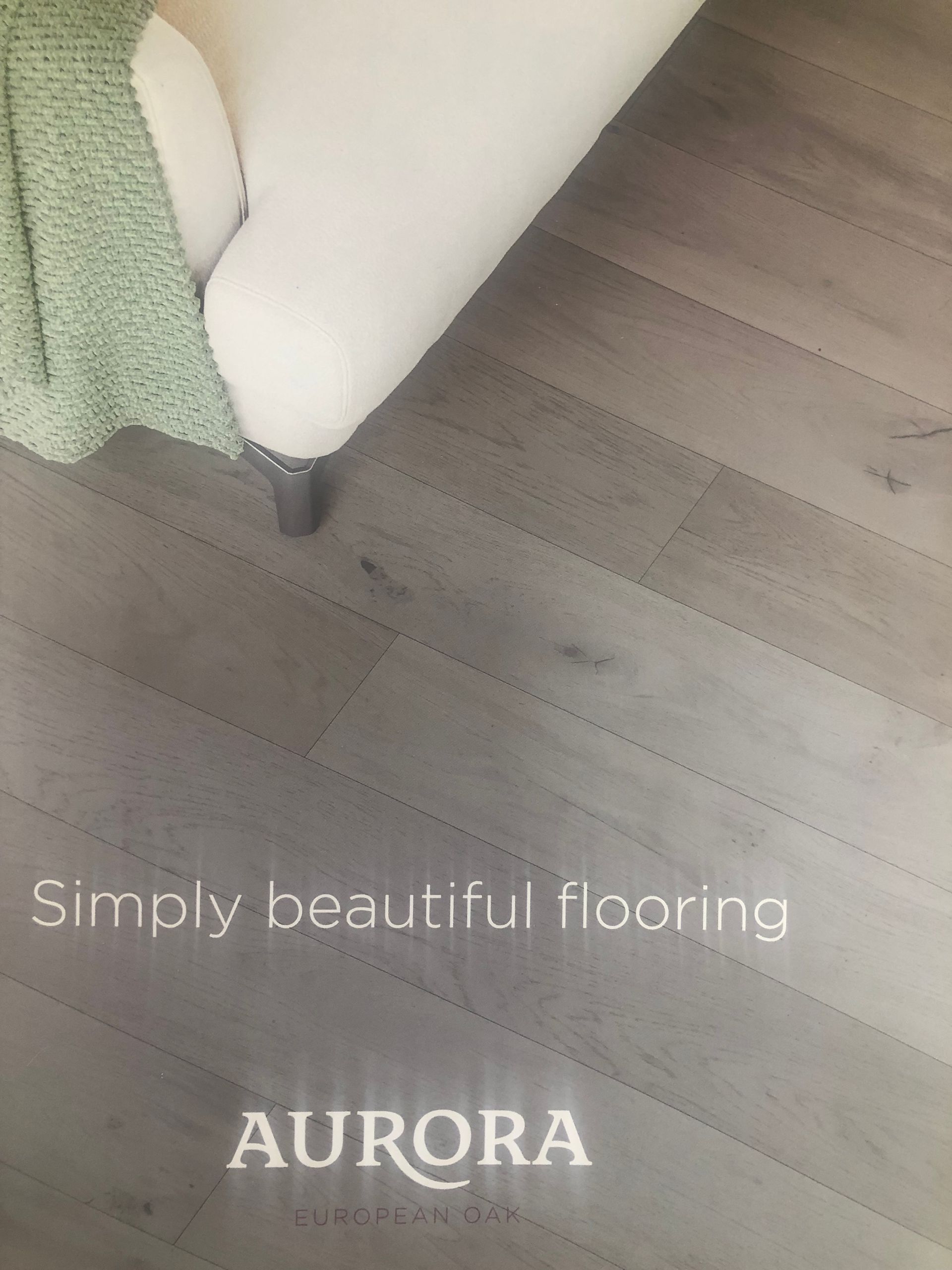 Light gray flooring next to a white armchair with a green blanket draped on it. Aurora logo.