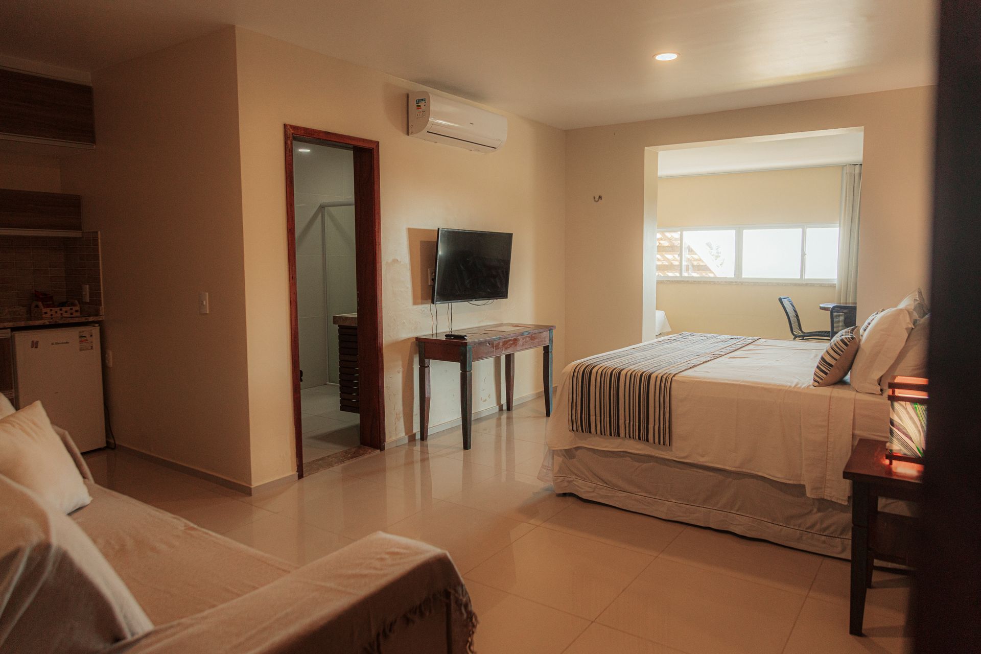 Hotel room with bed, sofa, TV, and balcony access.