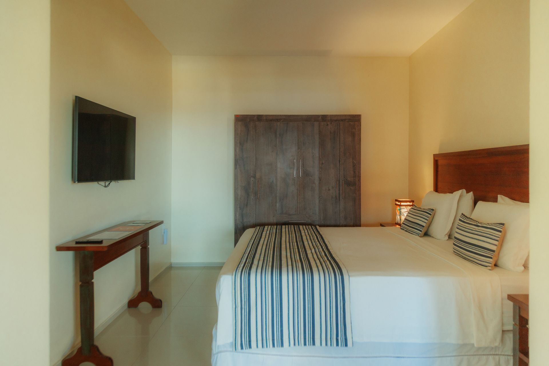 Bedroom with bed, TV on wall, and wooden side table.