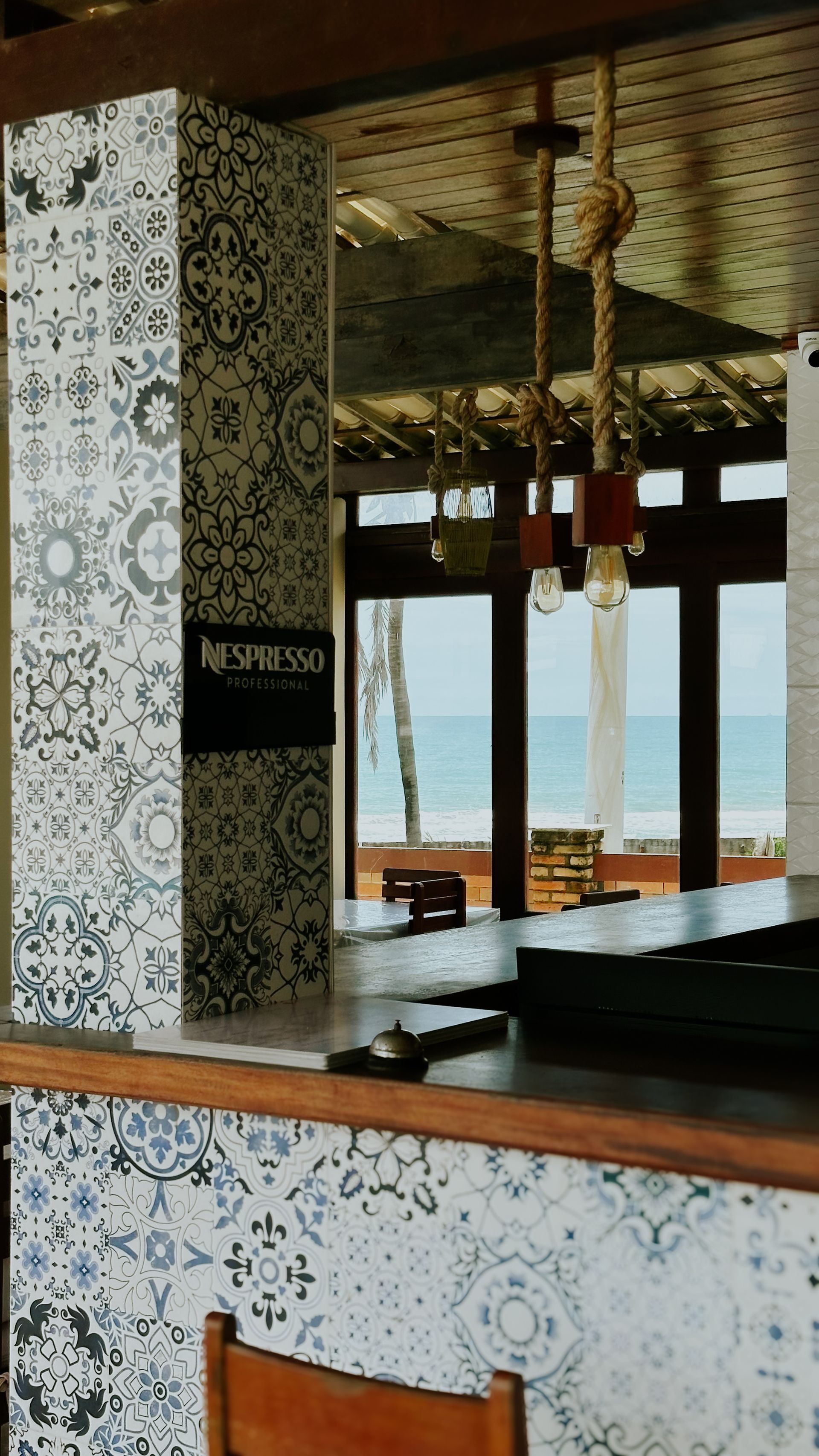 Bar interior with patterned tile, wood accents, and ocean view.