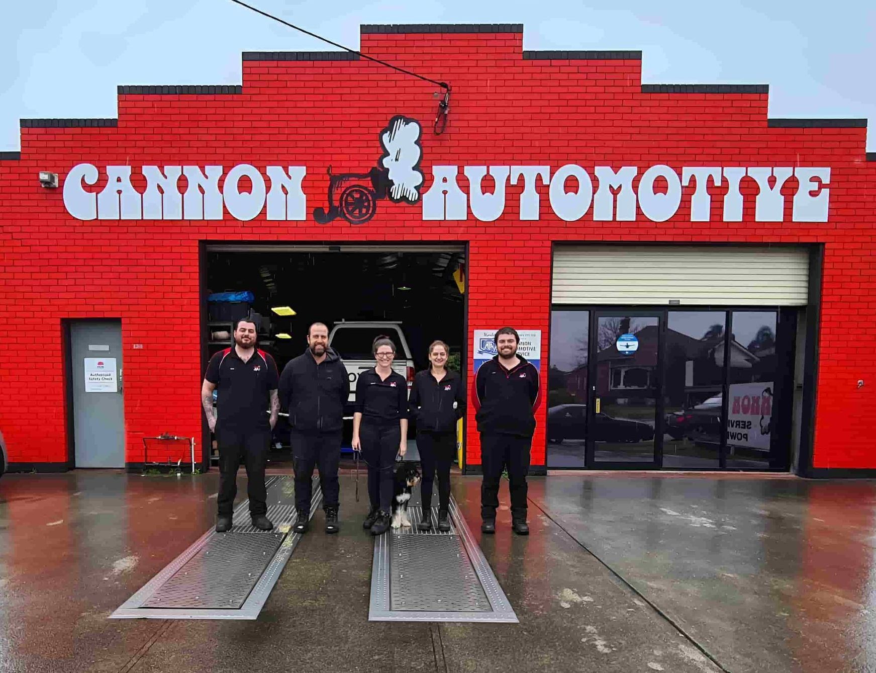 A Group Of People Are Posing In Front Of A Cannon Automotive — Cannon Automotive Services In East Maitland, NSW