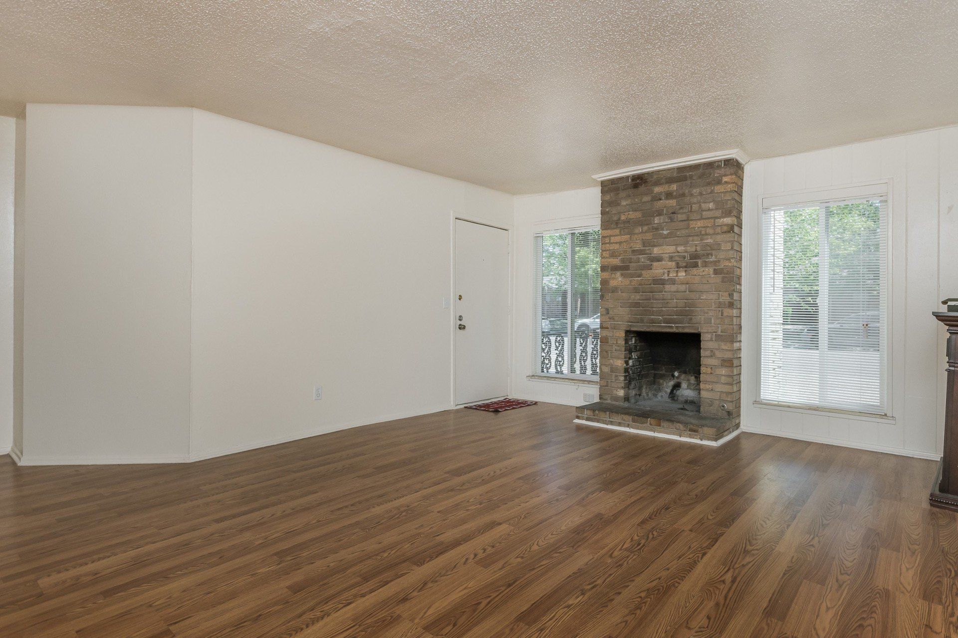 An empty living room with hardwood floors and a fireplace.