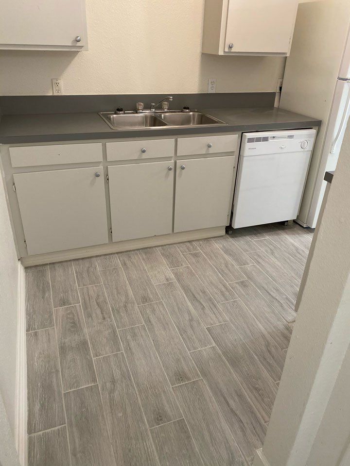 A kitchen with a sink , cabinets , and a dishwasher.