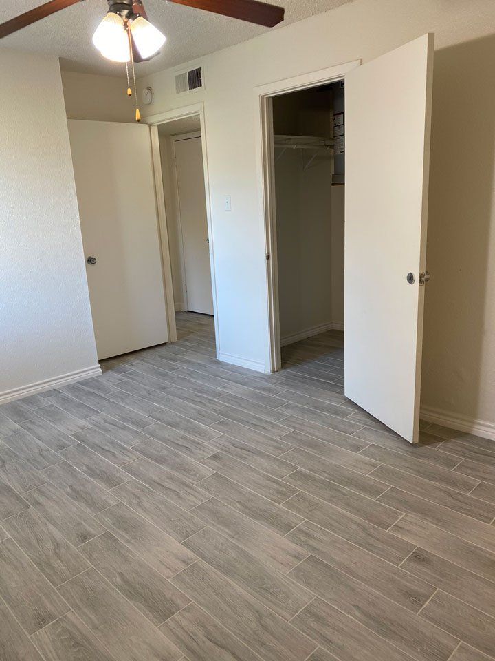 A bedroom with a ceiling fan and a closet.