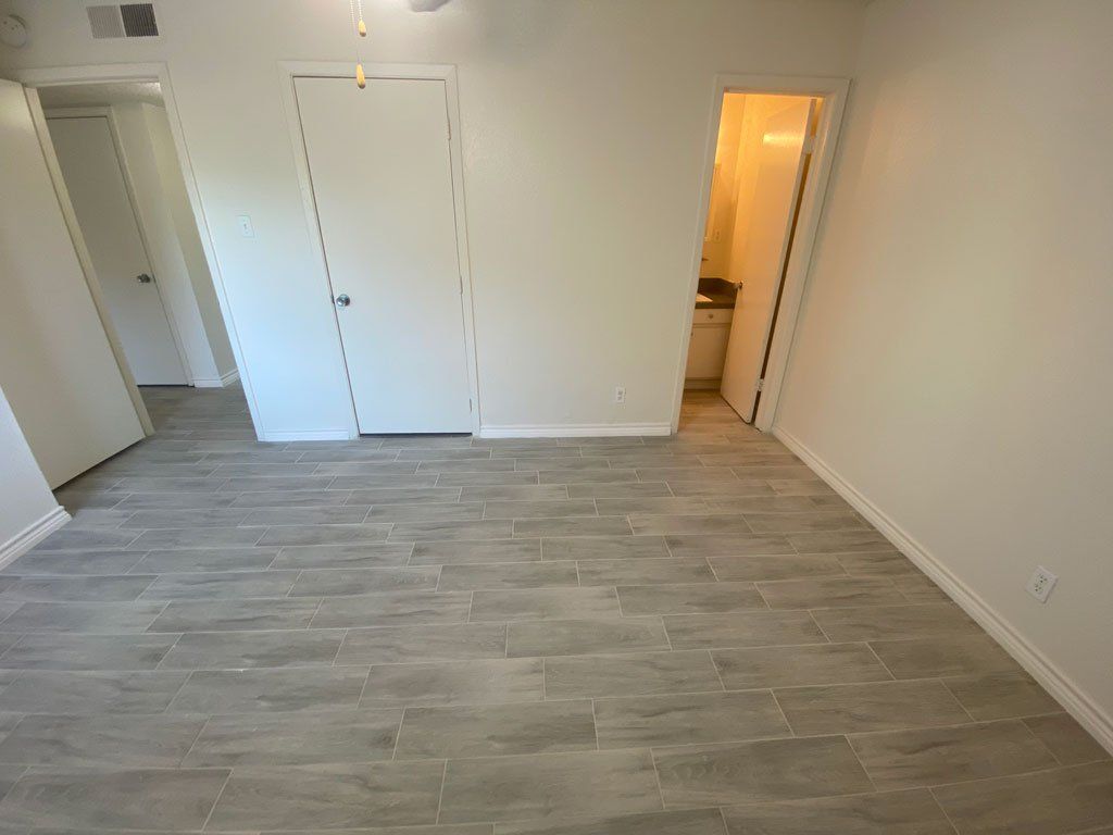 An empty room with a tiled floor and white walls.
