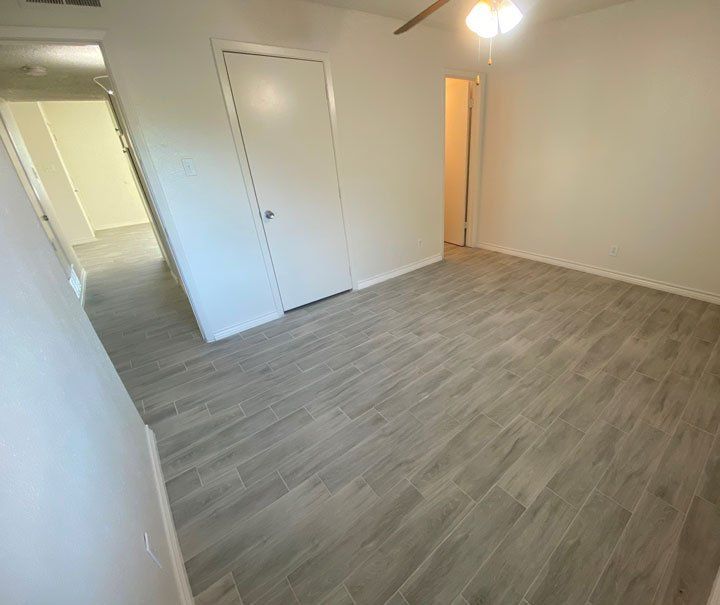 An empty room with faux hardwood floors and white walls.