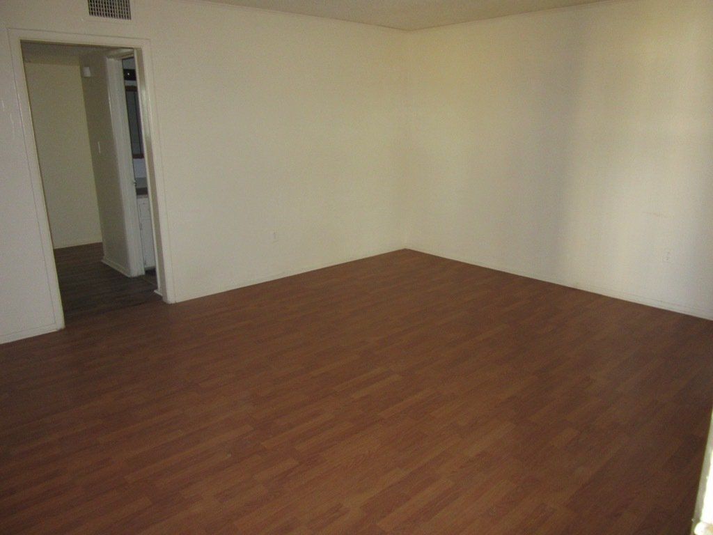 An empty room with hardwood floors and white walls.