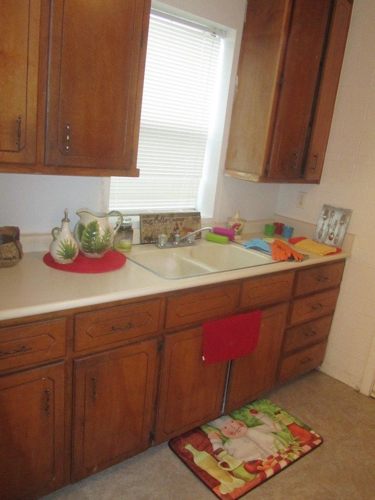 A kitchen with wooden cabinets and a rug on the floor
