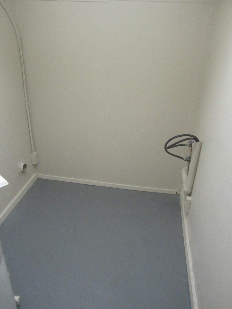 An empty room with a gray floor and white walls