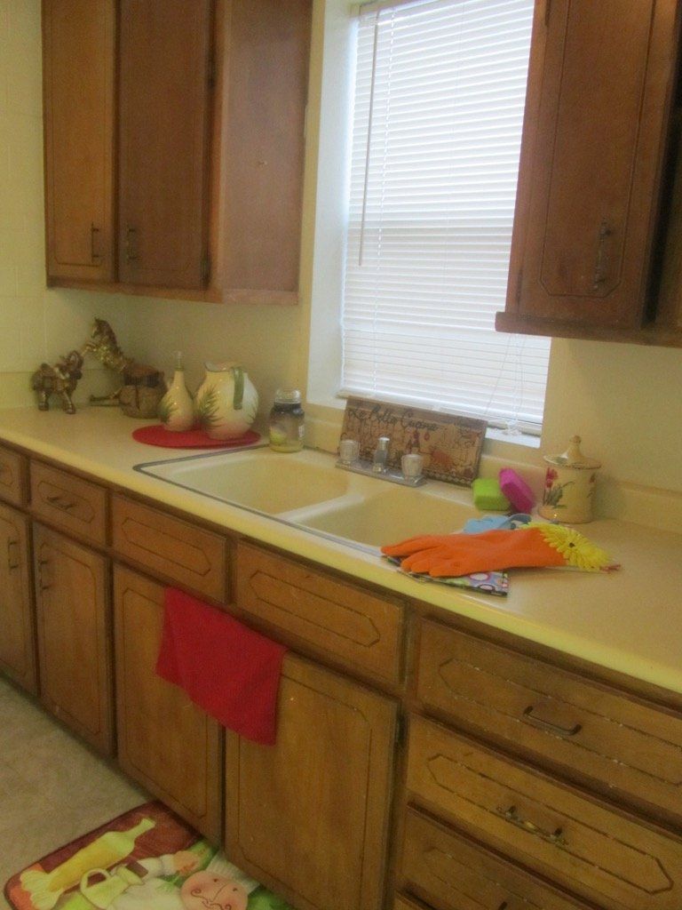 A kitchen with a sink , cabinets , drawers and a window.