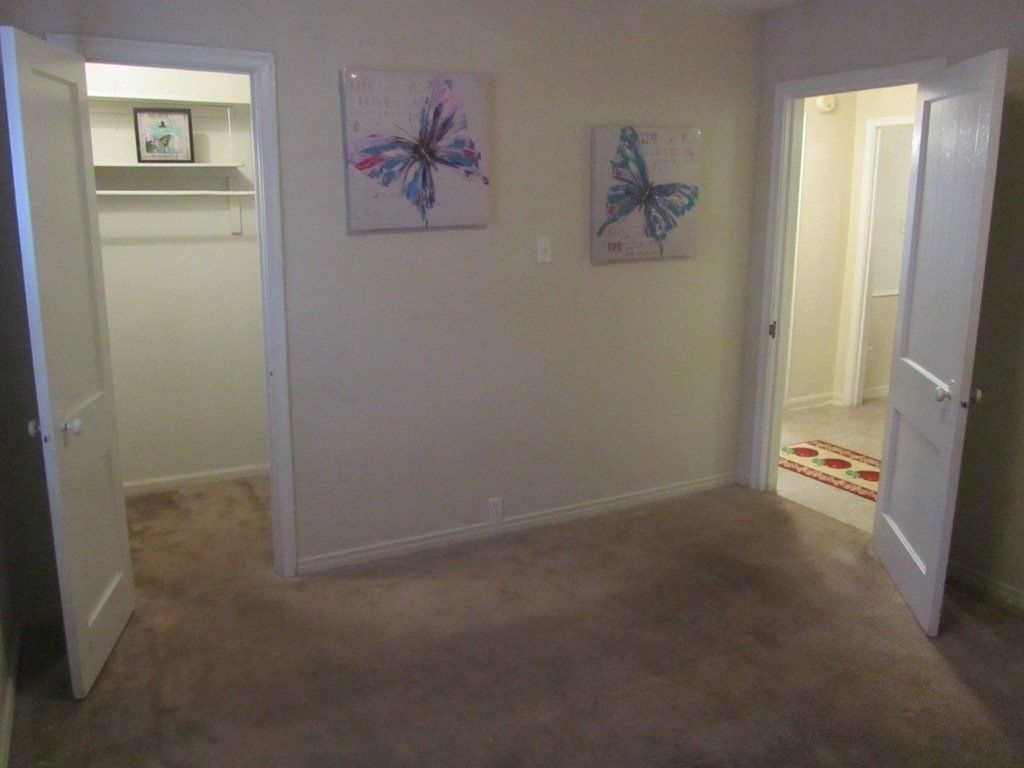 A bedroom with a walk in closet and two paintings on the wall.