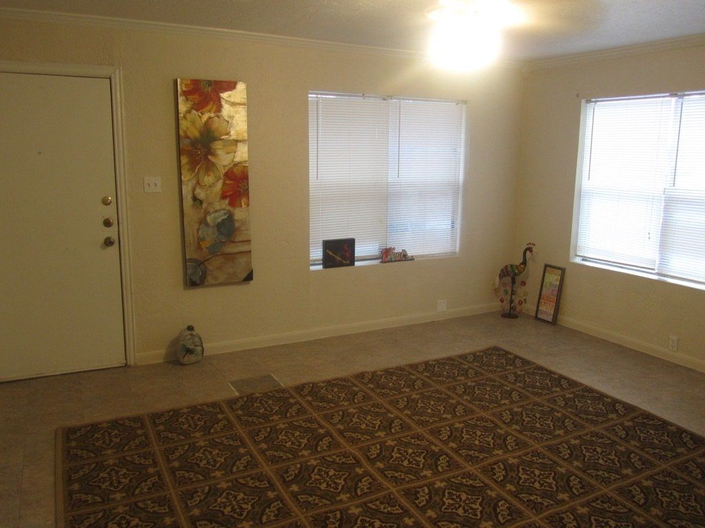 An empty living room with a rug and a painting on the wall.