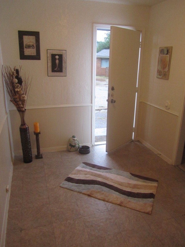 A hallway with a rug and a door that is open