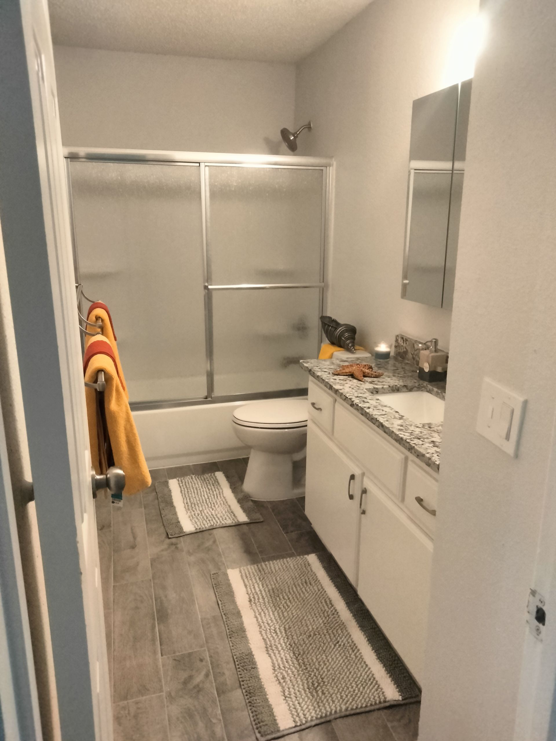 Large bathroom with ceramic tile flooring, tub & surround with frameless glass shower doors, a toilet , granite countertop with recessed sink