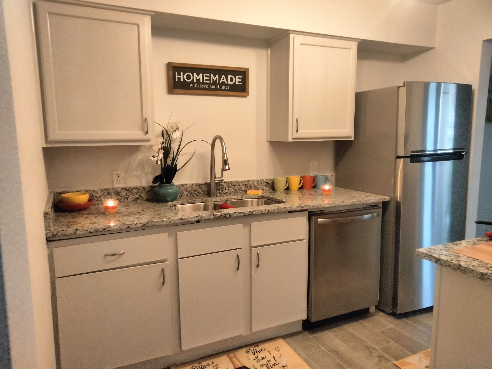 A kitchen with stainless steel appliances, granite countertop, gray color ceramic tile flooring
