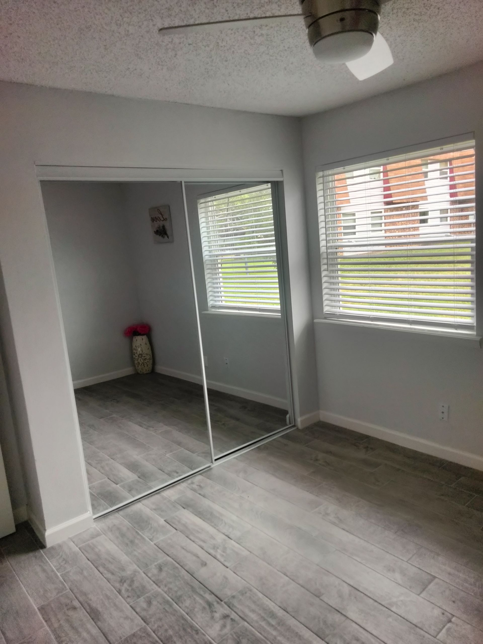 A bedroom with sliding mirrored closet doors, ceramic tile flooring and a ceiling fan at Lions Court Apartments in Wichita Falls TX