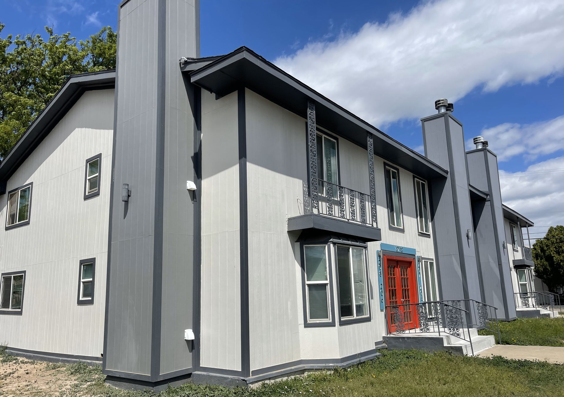 A white and gray apartment building with a red door