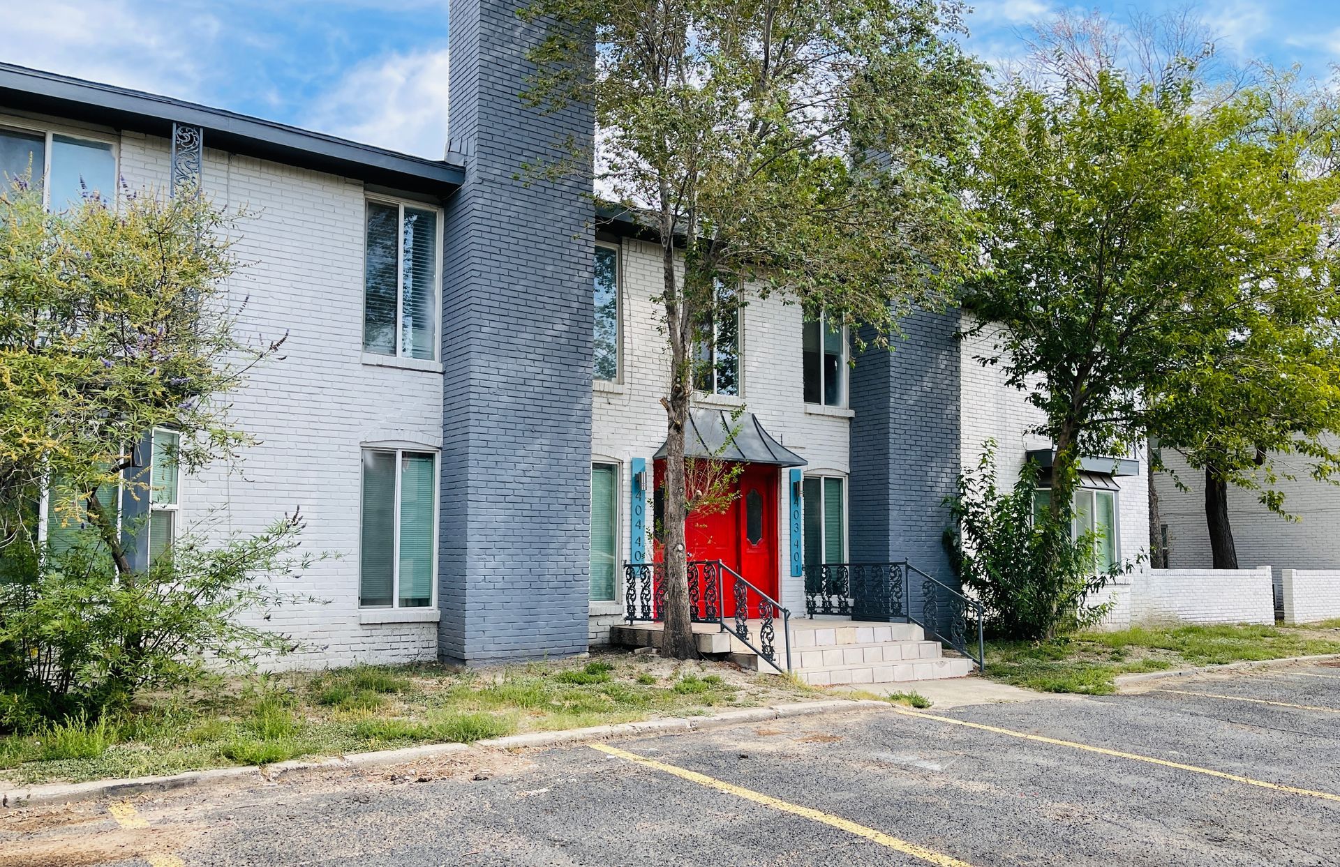 A large apartment building with a red door and a parking lot in front of it.