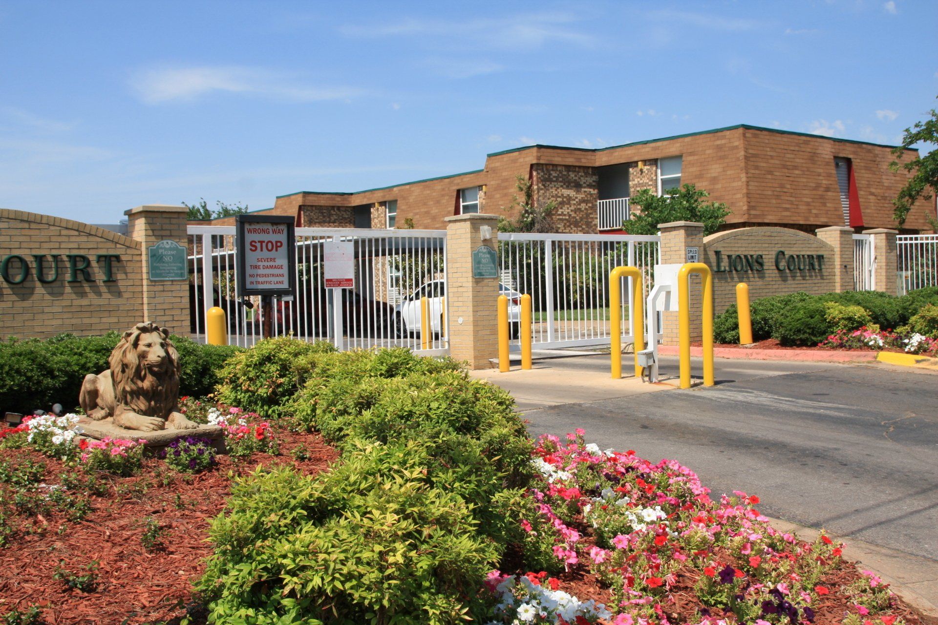 A lion statue is in front of a gated entrance to a building.