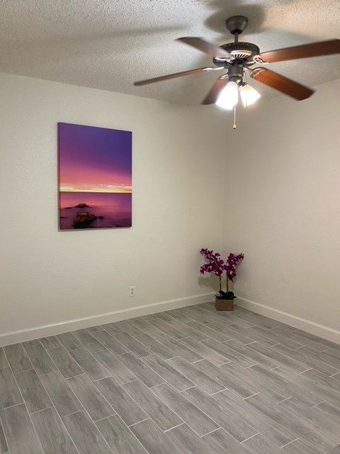 A bedroom with a ceiling fan and a picture on the wall