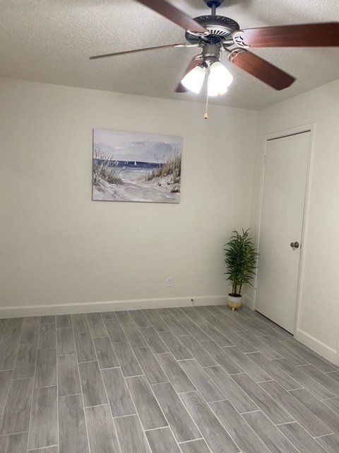 An empty room with a ceiling fan and a painting on the wall.