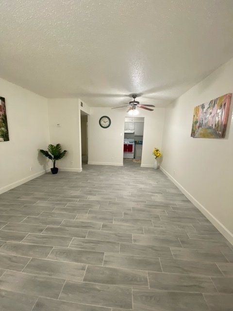 A living room with a clock on the wall and a ceiling fan.