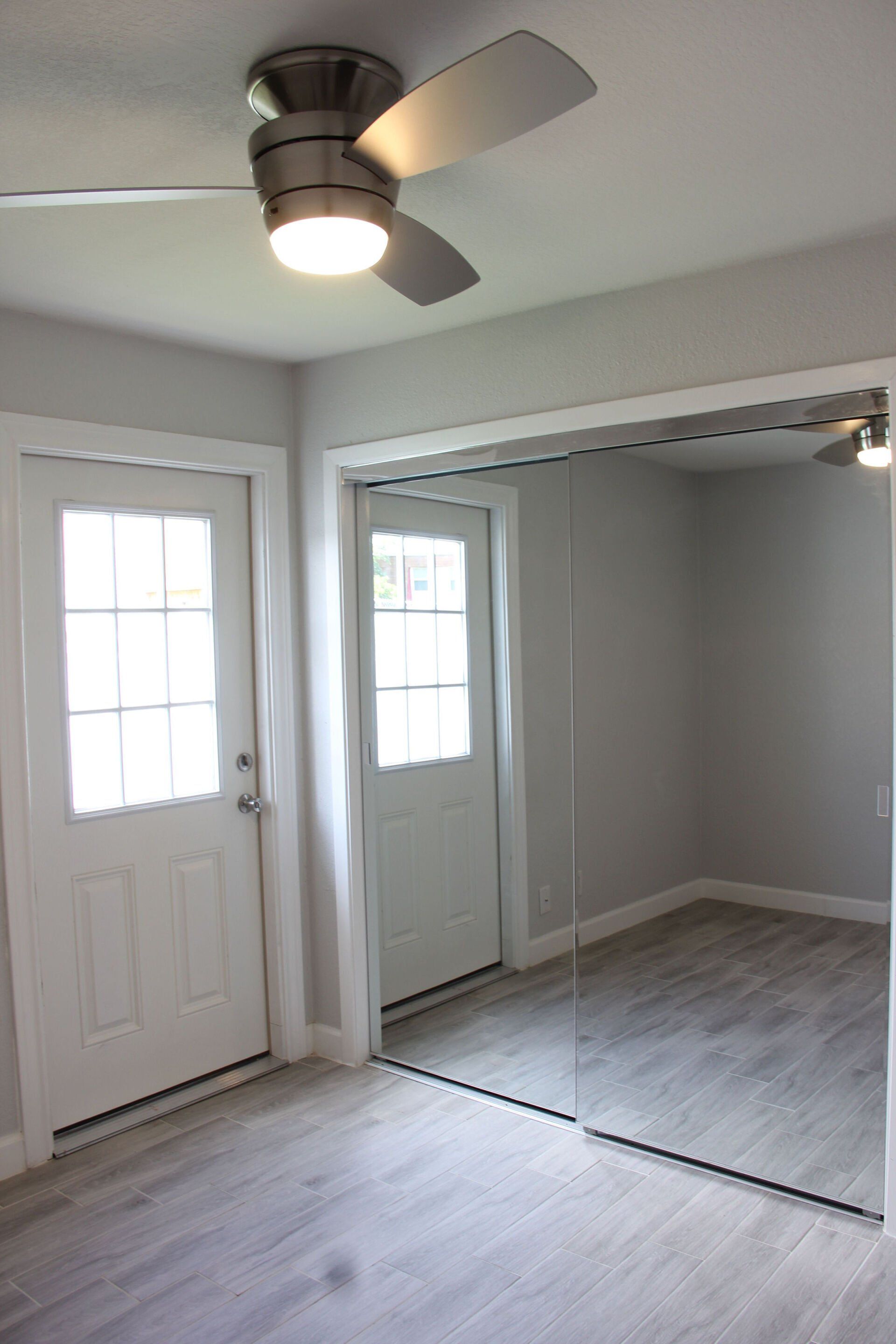 An empty room with a ceiling fan and mirrors.