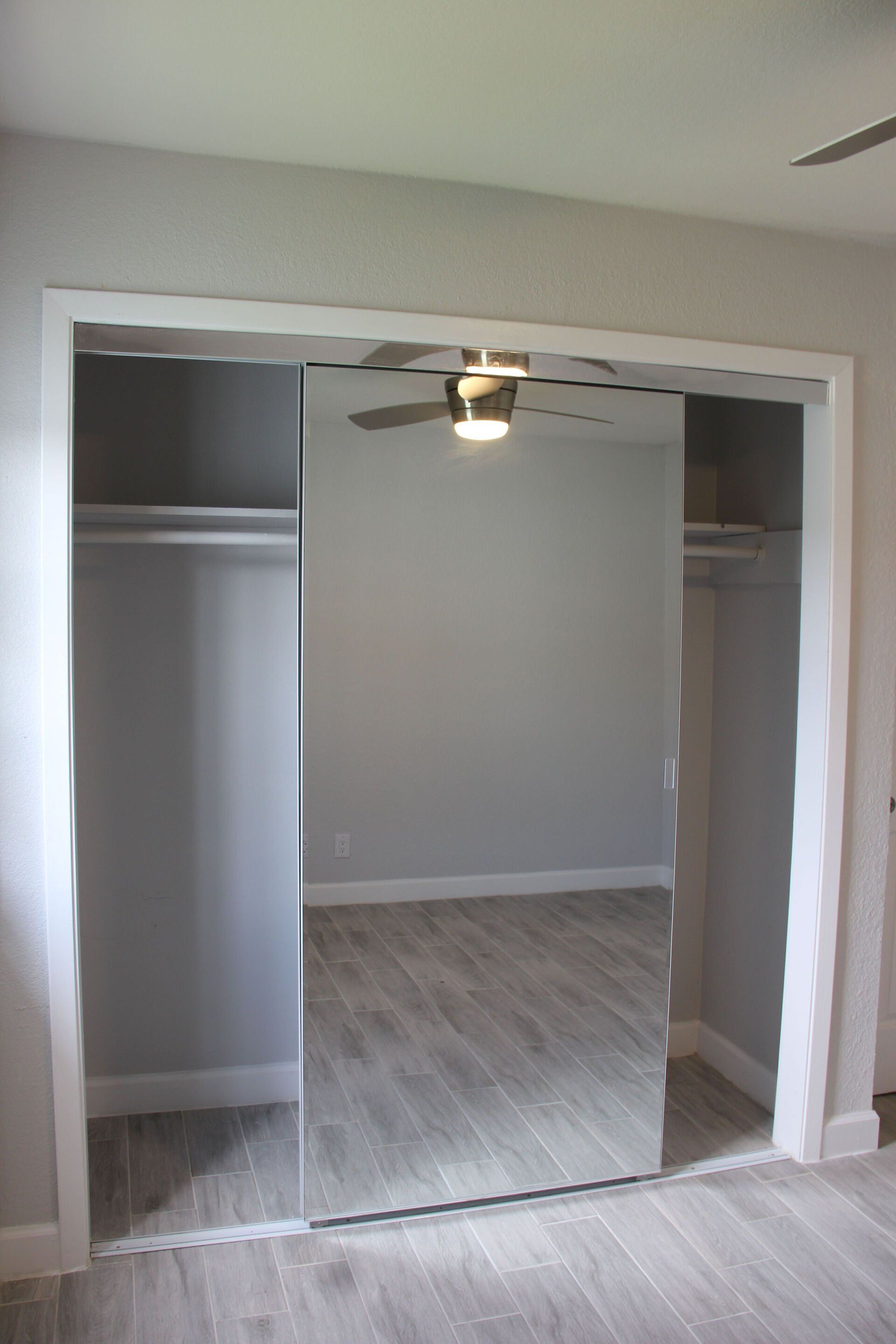 An empty closet with a large mirror and a ceiling fan.