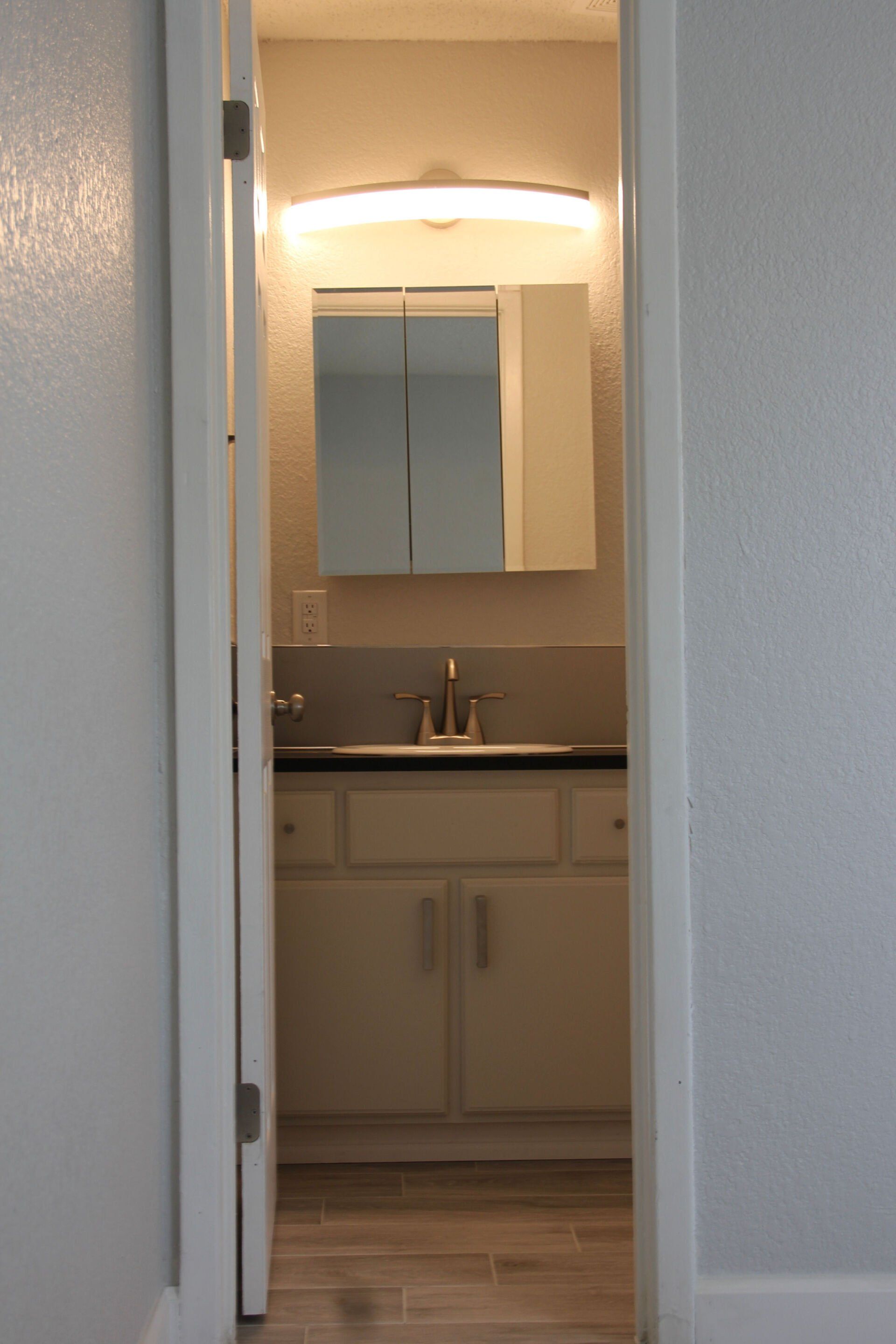 A bathroom with a sink , mirror and cabinets.