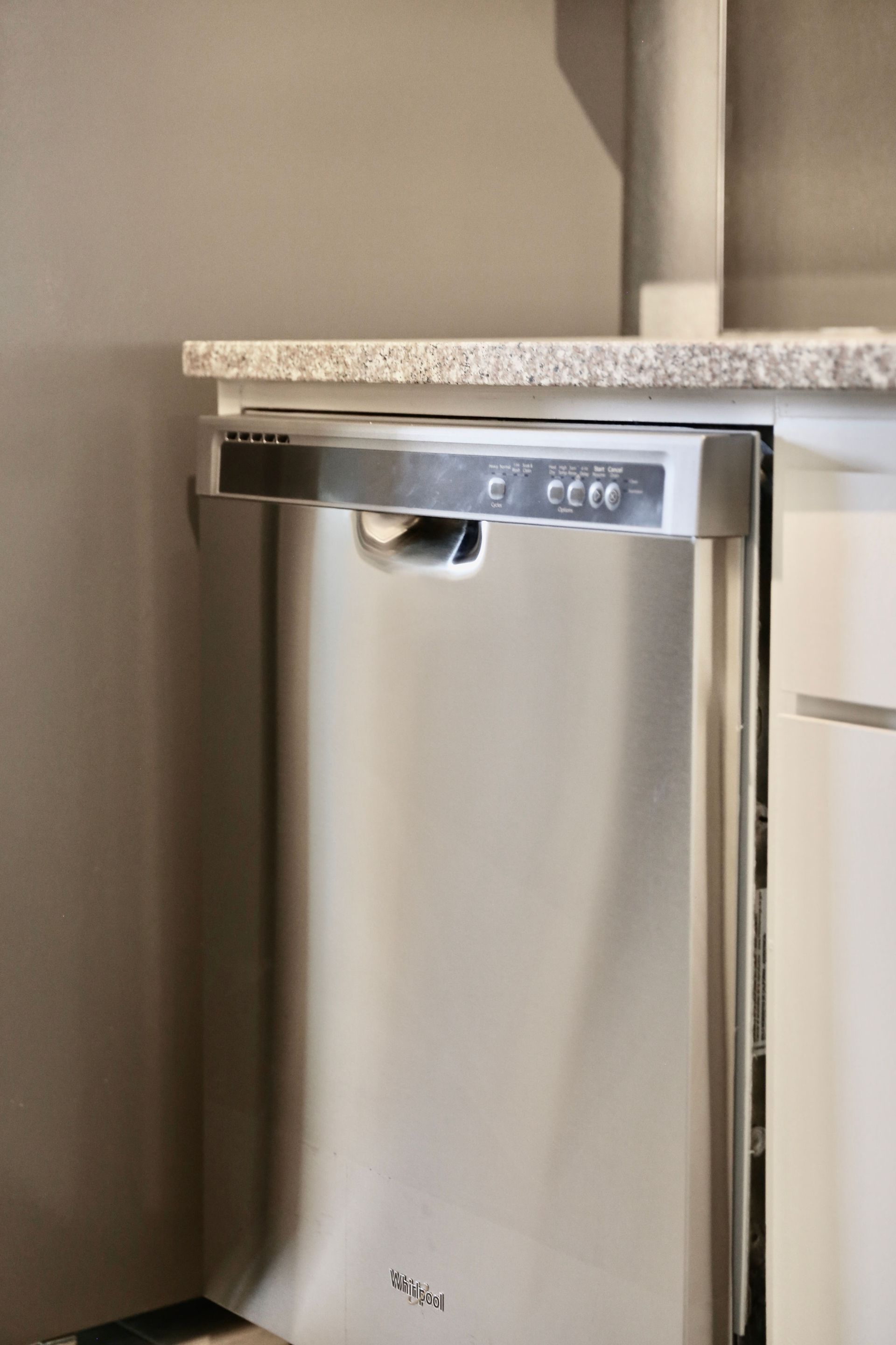 A stainless steel dishwasher is sitting under a granite counter in a kitchen of Luxury upgraded unit