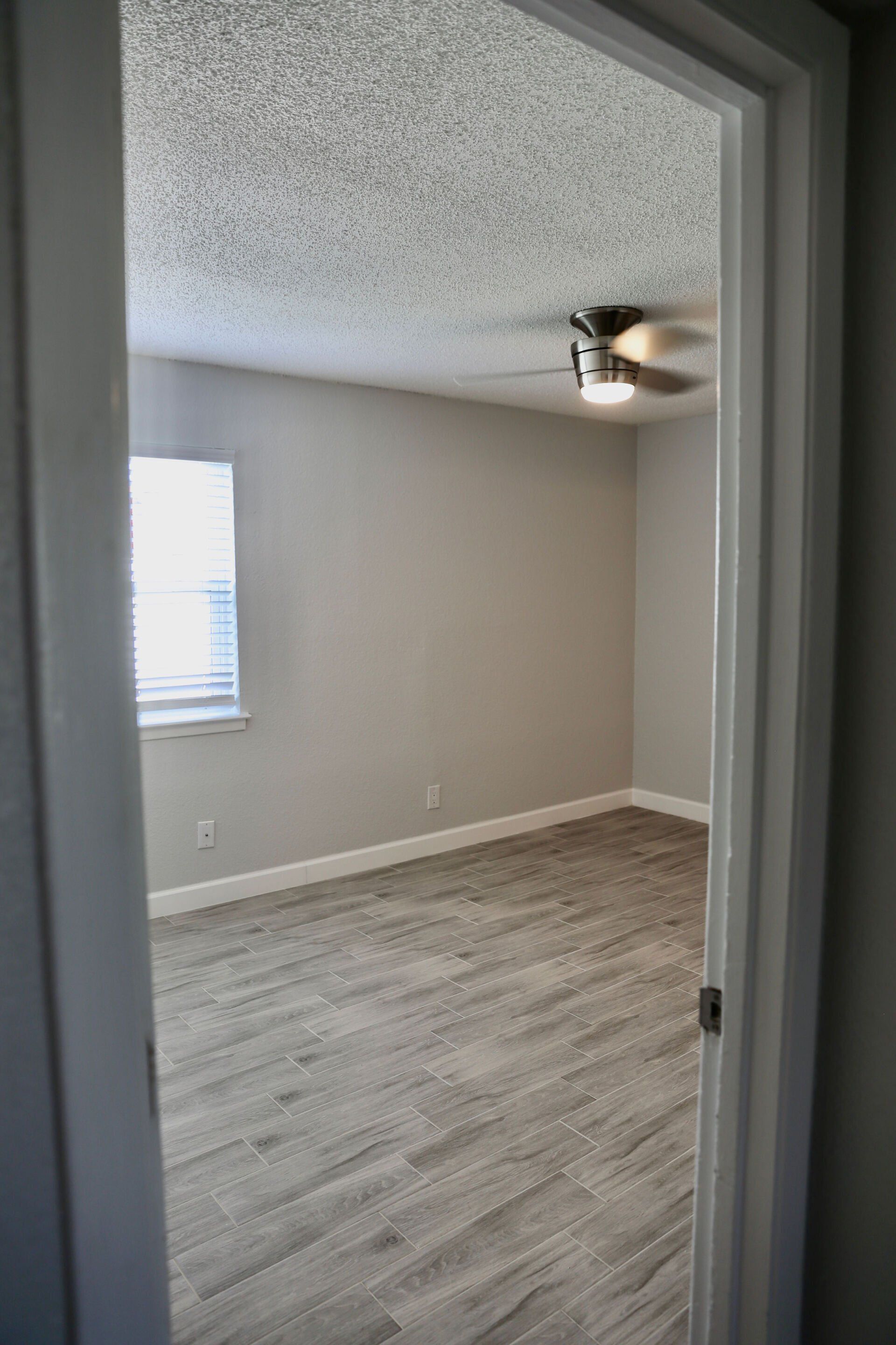 A bedroom with a ceiling fan and a window.