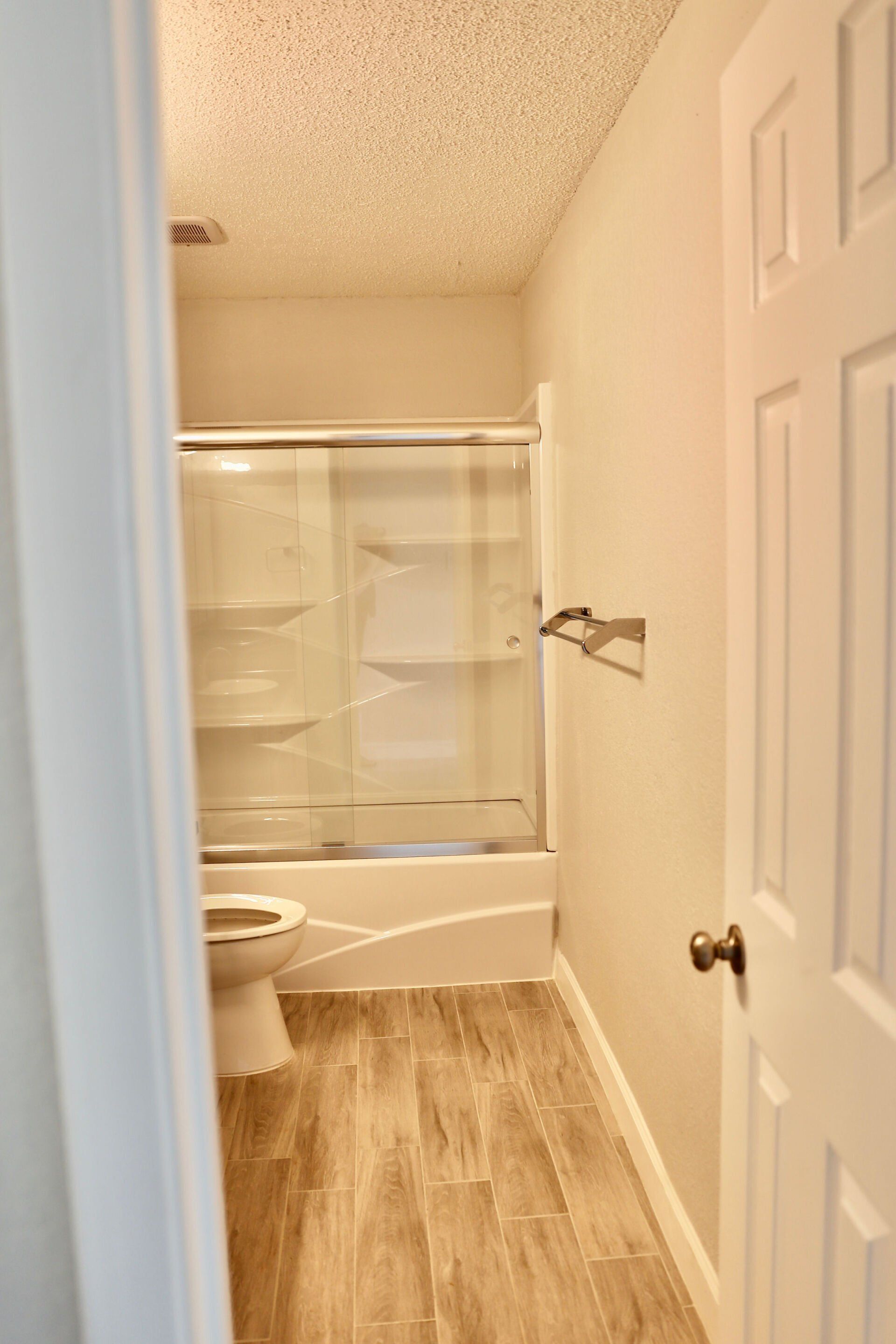 A bathroom with a toilet , shower and bathtub.