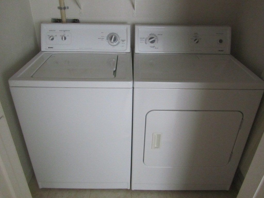A washer and dryer are sitting next to each other in a closet.