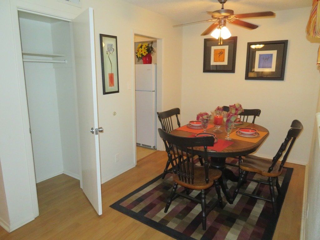 image of dining area with ceiling fan & light in our apartments, small kitchen table & chairs and a guest coat closet at Lions Court Apartments in Wichita Falls, TX