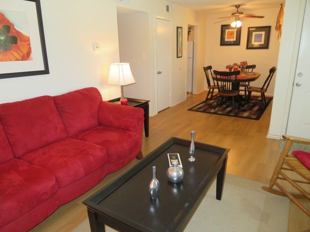 image of decorated living room with couch and attached dining room area with ceiling fan with light at Lions Court Apartments