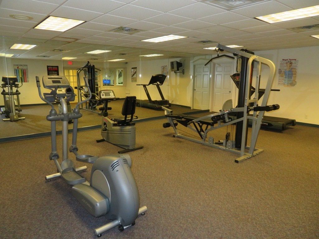 complex gym with stationary bike & multi station exercise equipment & mirrored wall at lions court apartments in Wichita Falls, TX