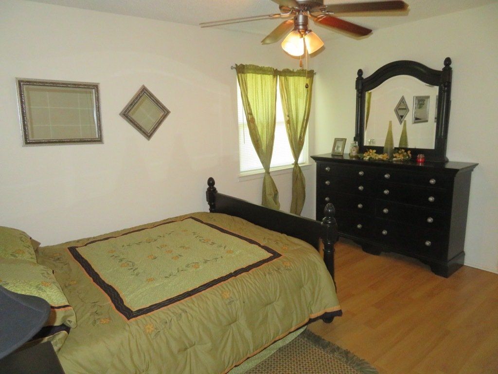 image of master bedroom with ceiling fan with light and hardwood laminate flooring at lions court apartments in Wichita Falls, TX