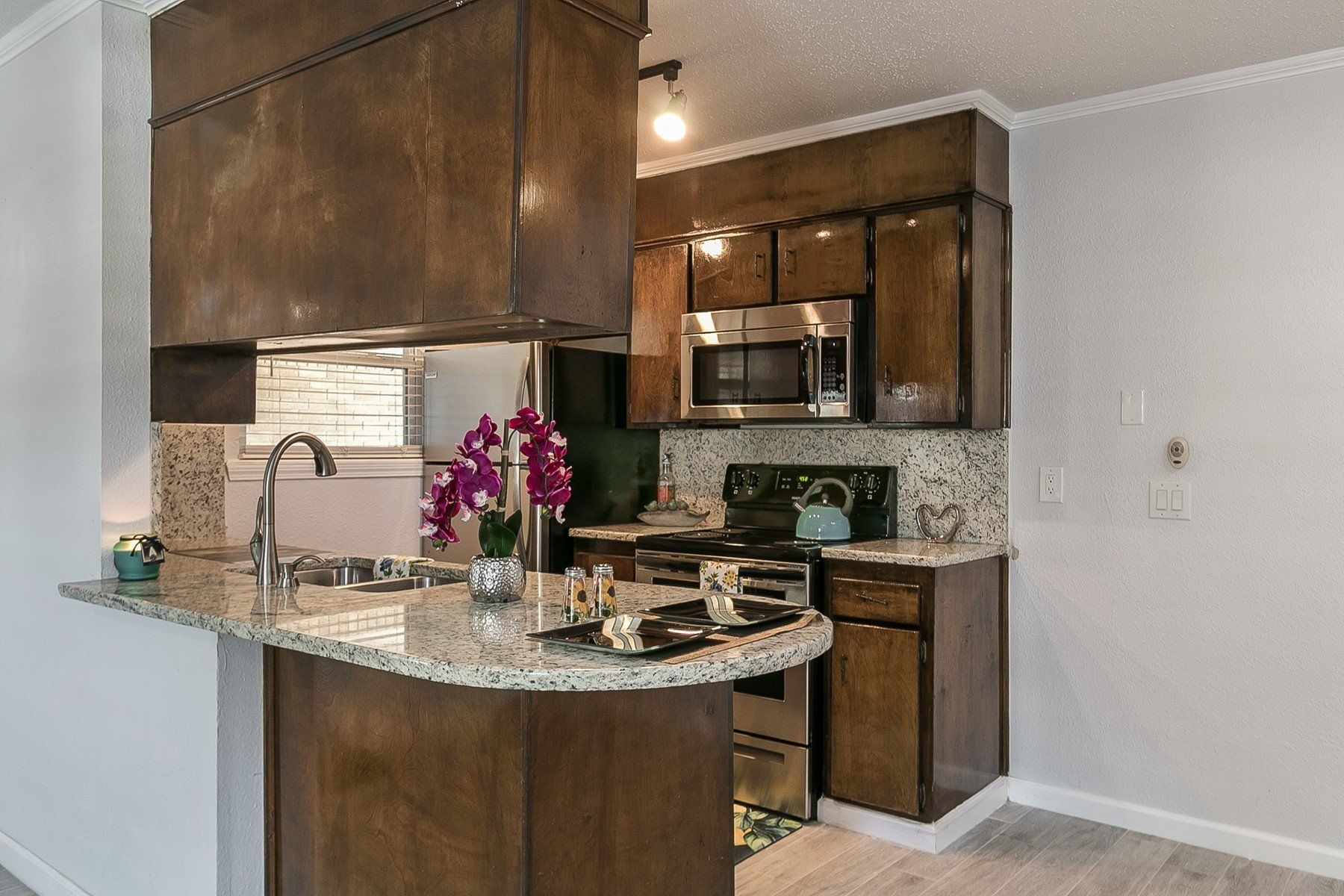Beautiful dark stained cabinetry with white walls, in the kitchen area at Summerwood Terrace Apartments in Amarillo, TX