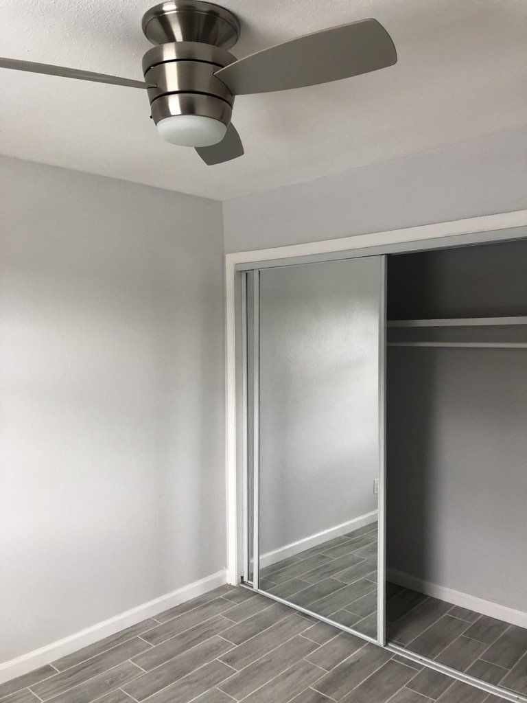 A bedroom with a ceiling fan and sliding glass doors.