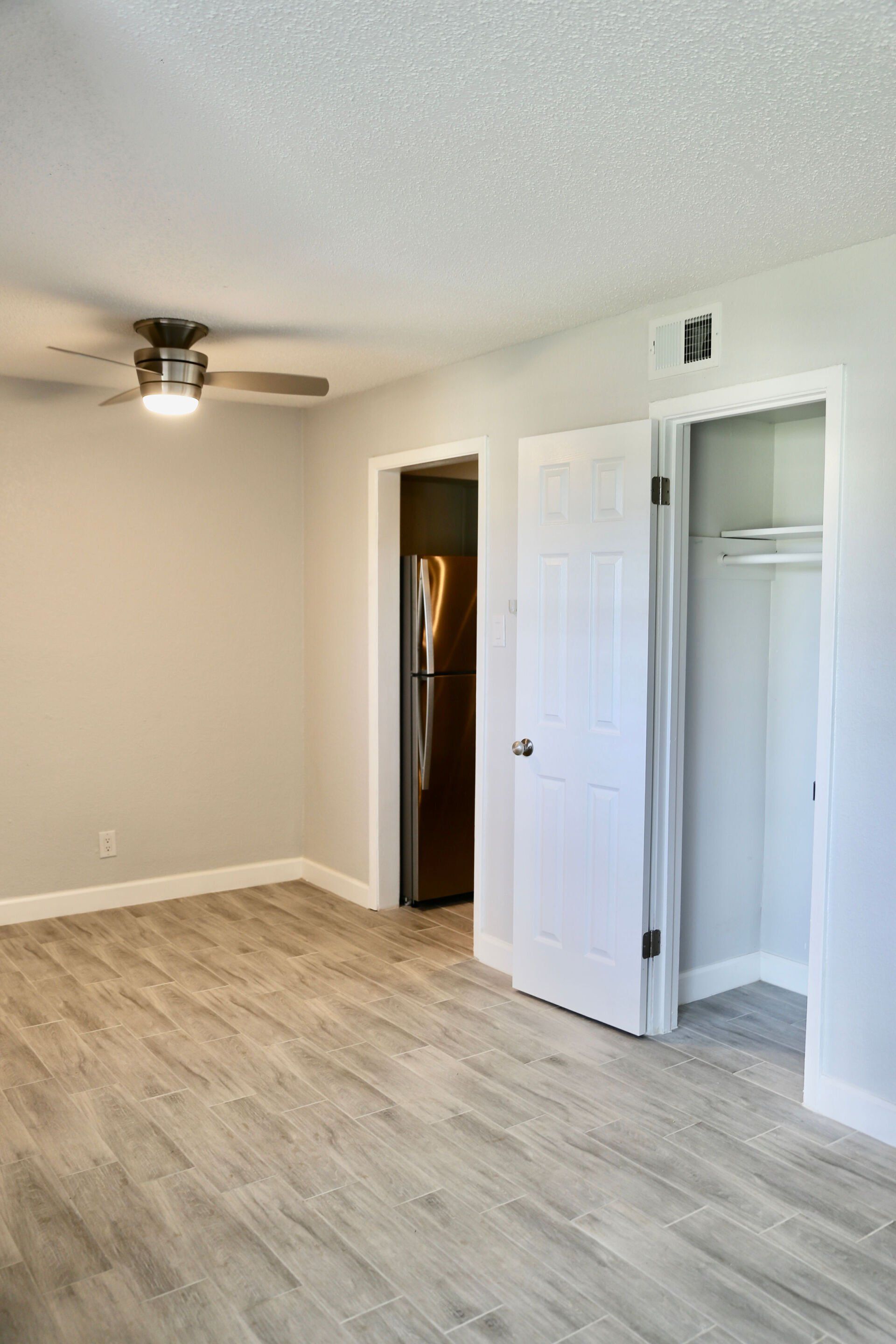 An empty room with hardwood floors and a ceiling fan.
