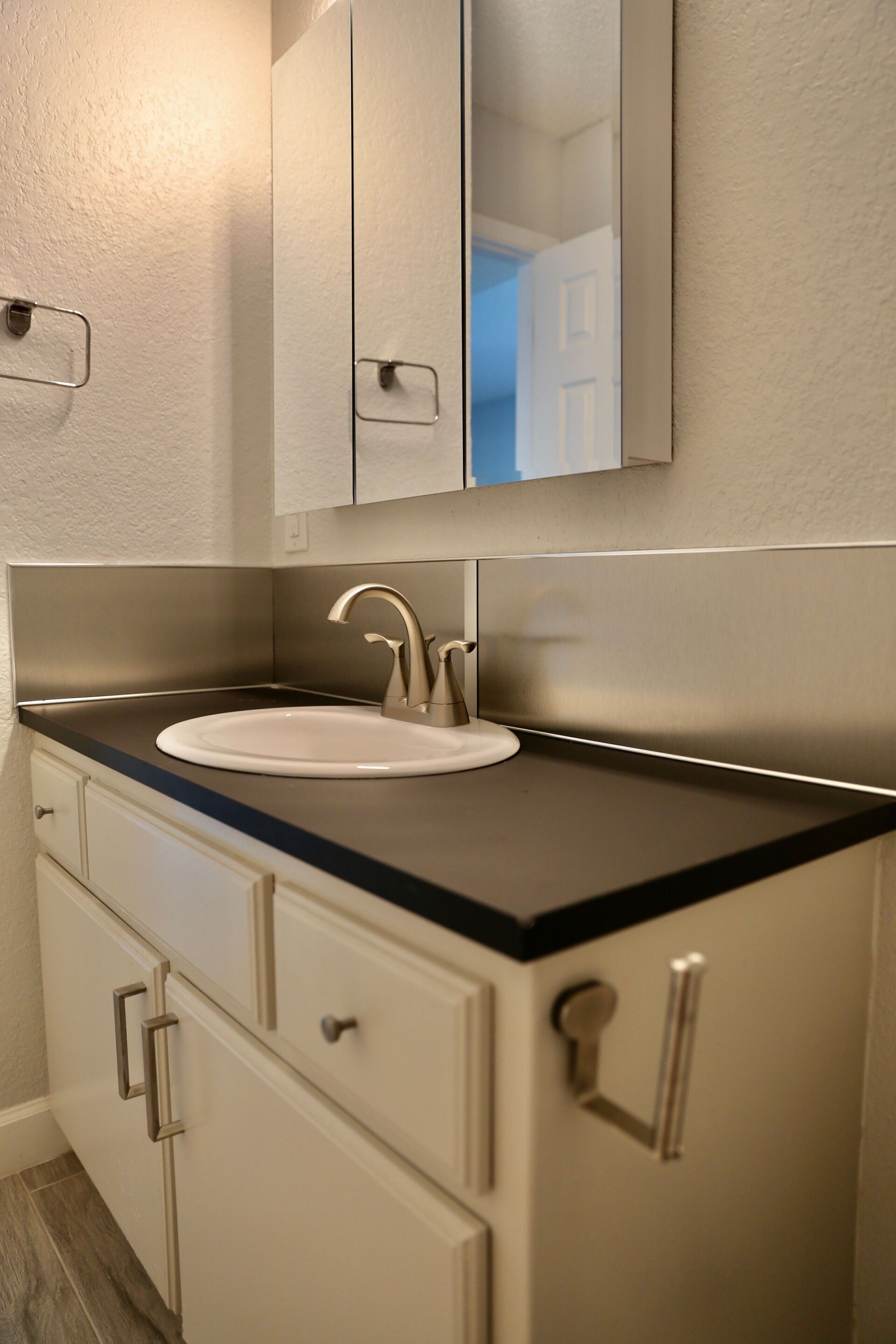 A bathroom with a sink , mirror and cabinets