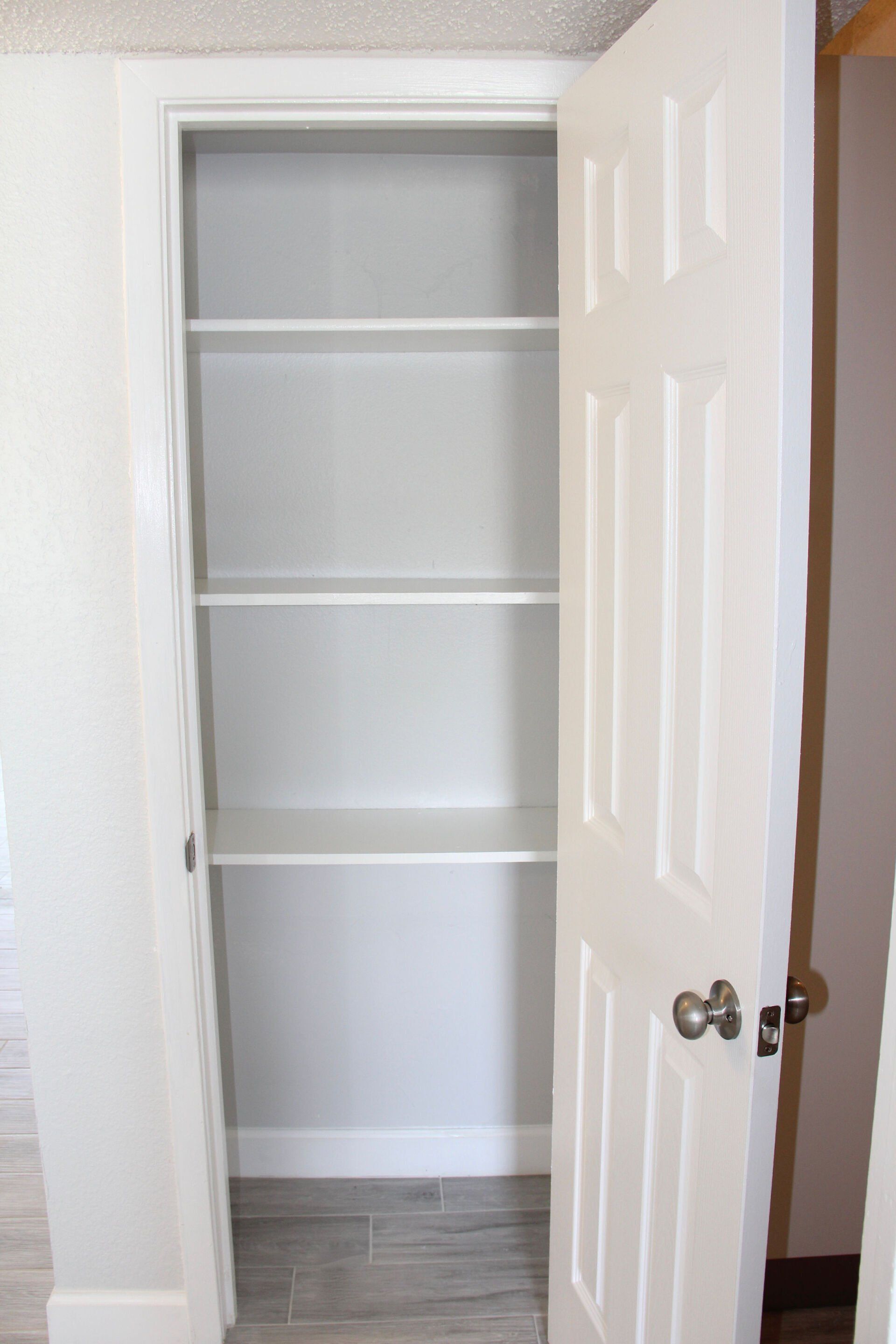 An empty closet with a door open and shelves.