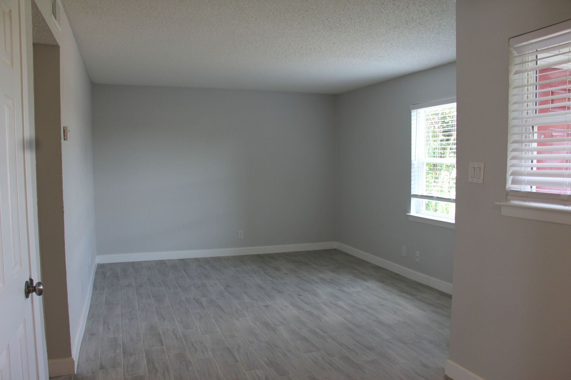 An empty living room with a window and blinds