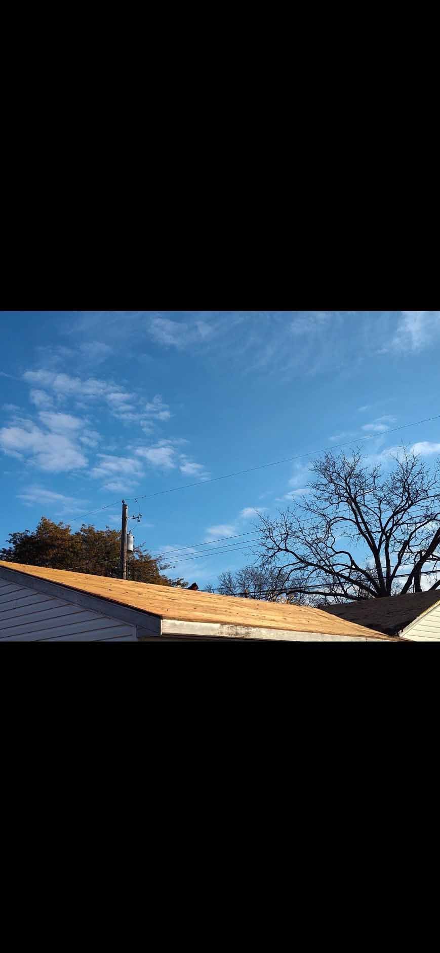 A bright blue sky with scattered clouds and a tree. A rooftop is in the foreground.