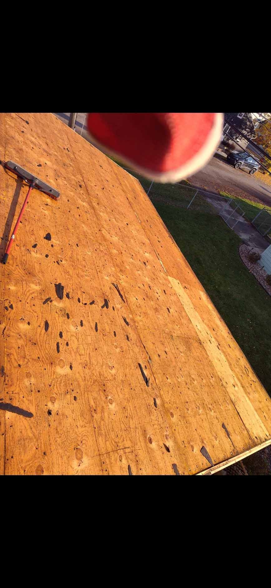 Rooftop covered in wooden planks with tool and red object at the top, taken from a high angle.