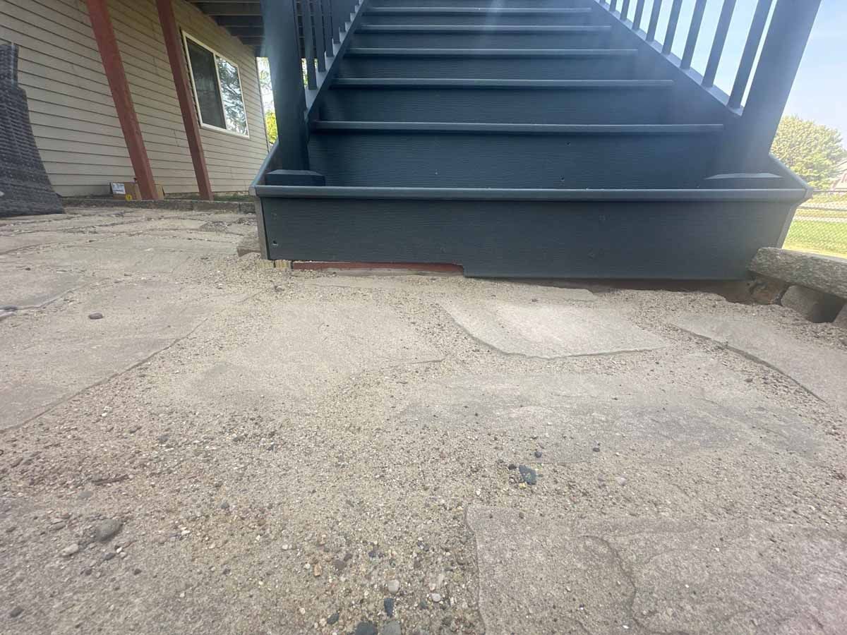 Staircase with gray steps and base sits on a sandy, cracked ground.