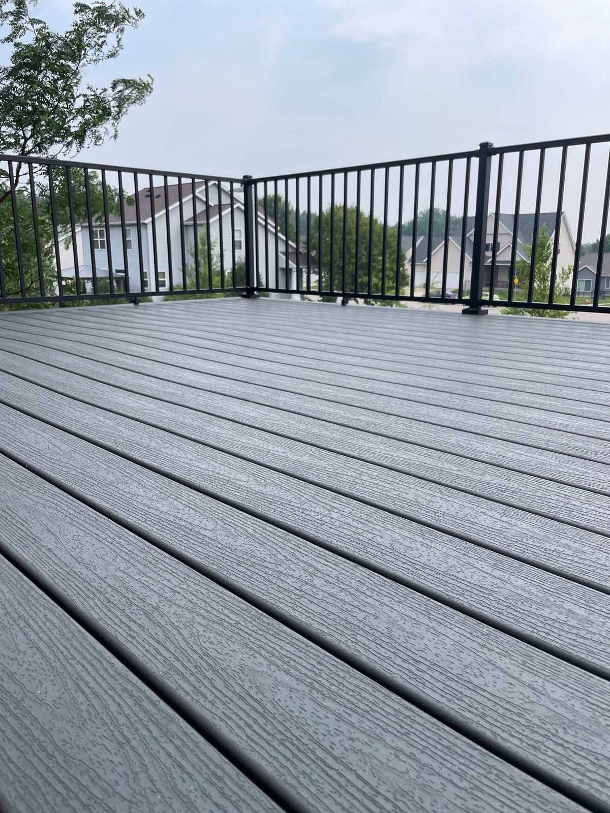 Gray composite deck with black railing overlooking a residential neighborhood.