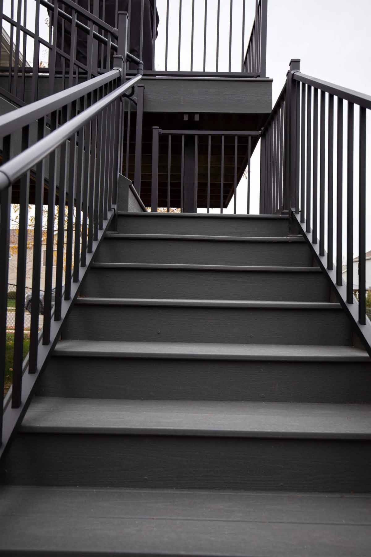 Gray outdoor stairs with black railings leading upwards.