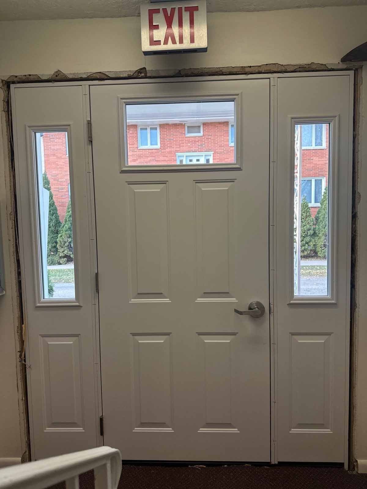 White exit door with sidelights, window above, and illuminated 